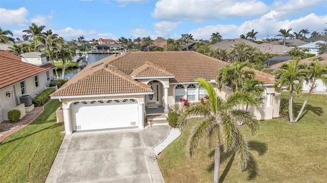 mediterranean / spanish home with a tile roof, stucco siding, a water view, a garage, and driveway