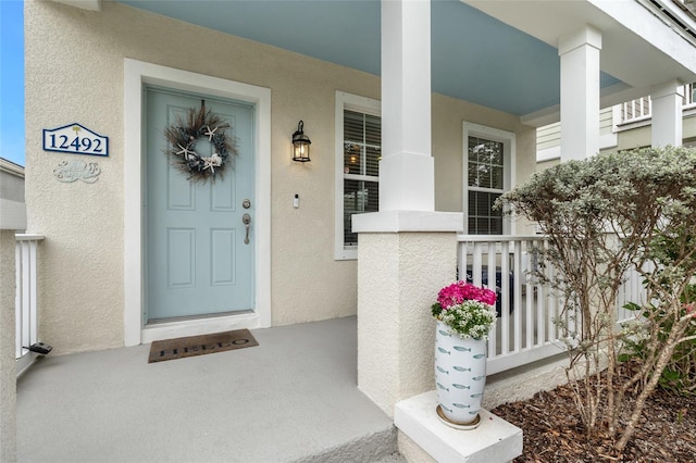 entrance to property featuring a porch and stucco siding