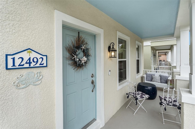 view of exterior entry featuring covered porch and stucco siding