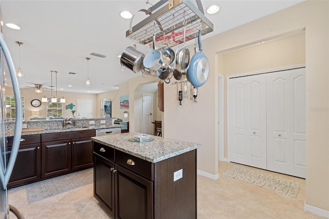 kitchen featuring arched walkways, visible vents, a sink, dark brown cabinets, and stainless steel fridge