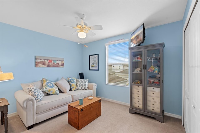 living area featuring carpet, baseboards, and a ceiling fan