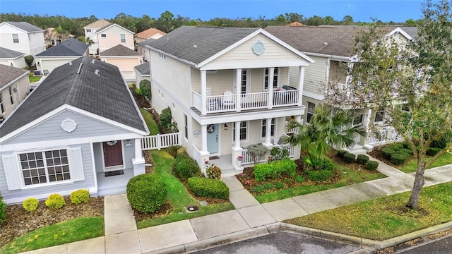 view of front of property featuring a porch, a shingled roof, a residential view, and a balcony