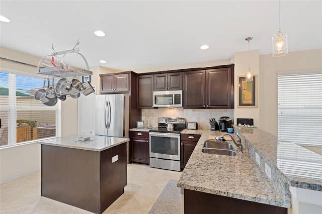 kitchen with tasteful backsplash, decorative light fixtures, stainless steel appliances, dark brown cabinets, and a sink