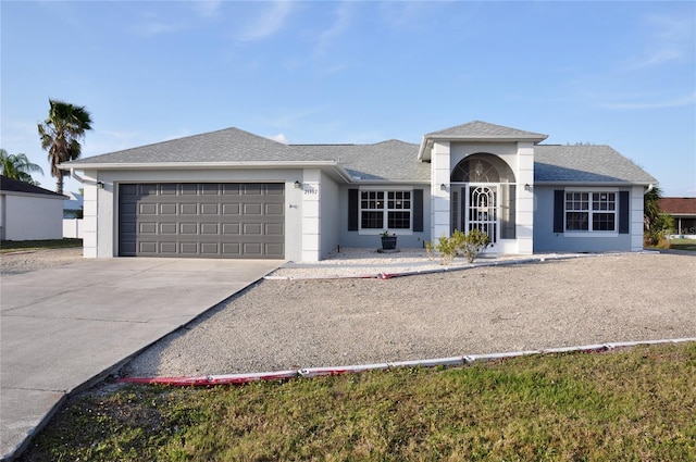 ranch-style home featuring an attached garage, a shingled roof, concrete driveway, and stucco siding