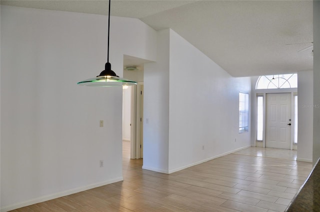 foyer featuring light wood-type flooring, vaulted ceiling, and baseboards