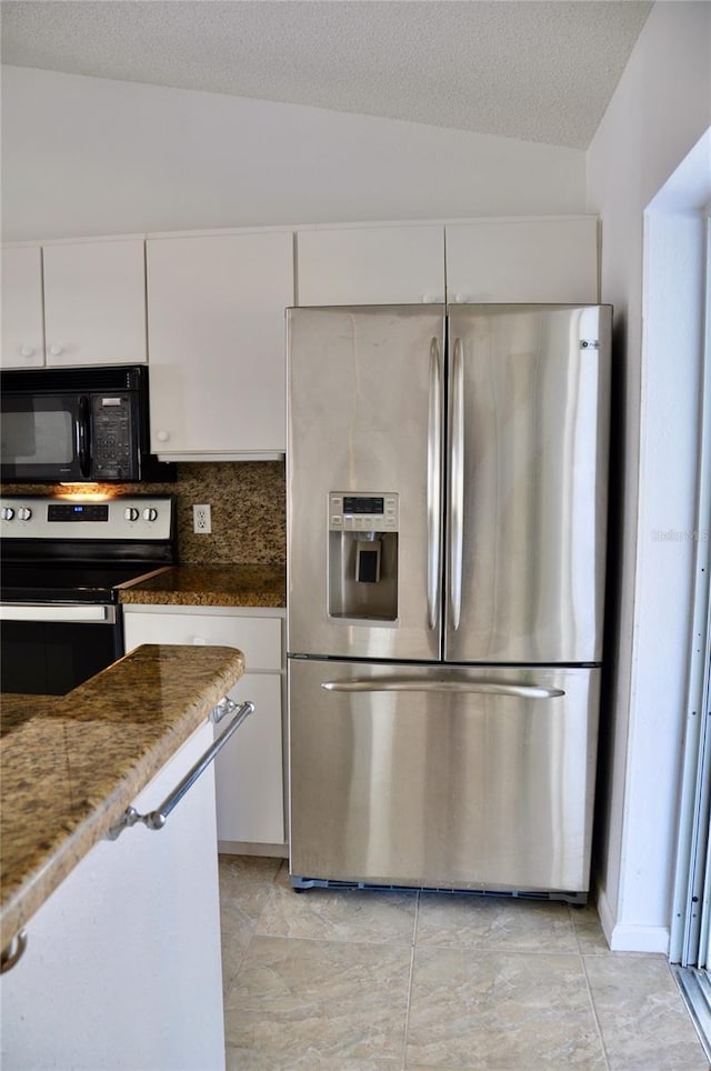 kitchen with white cabinetry, stainless steel appliances, a textured ceiling, and dark stone counters