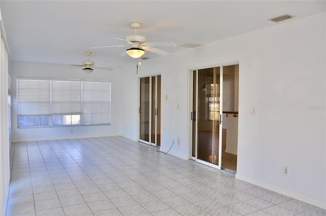 spare room with baseboards, visible vents, and a ceiling fan