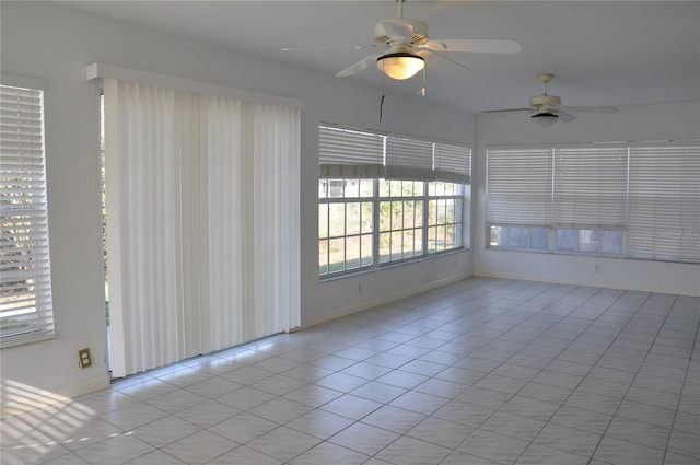 spare room featuring light tile patterned floors, ceiling fan, and baseboards