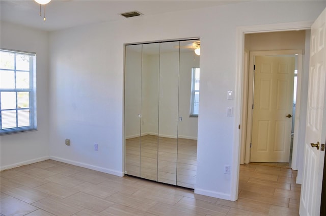 unfurnished bedroom with baseboards, visible vents, and a closet