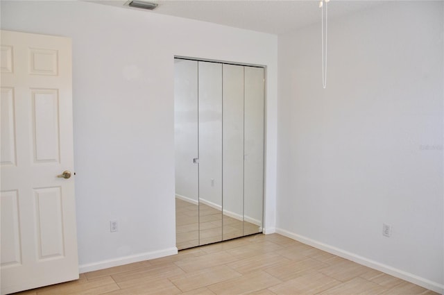 unfurnished bedroom featuring a closet, light wood-type flooring, visible vents, and baseboards