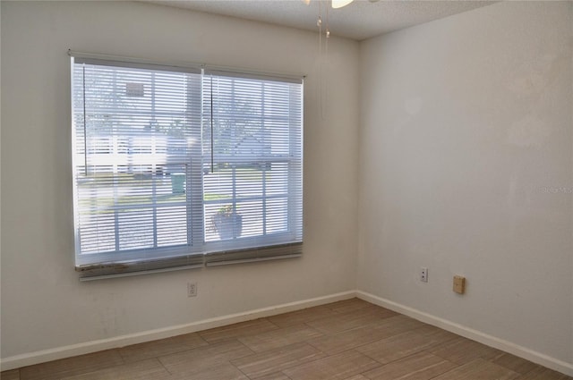 empty room featuring ceiling fan, baseboards, and wood finished floors