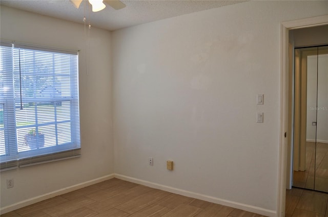 spare room with baseboards, a textured ceiling, a ceiling fan, and light wood-style floors