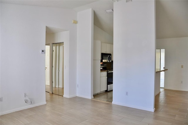 interior space featuring high vaulted ceiling, light wood finished floors, and baseboards