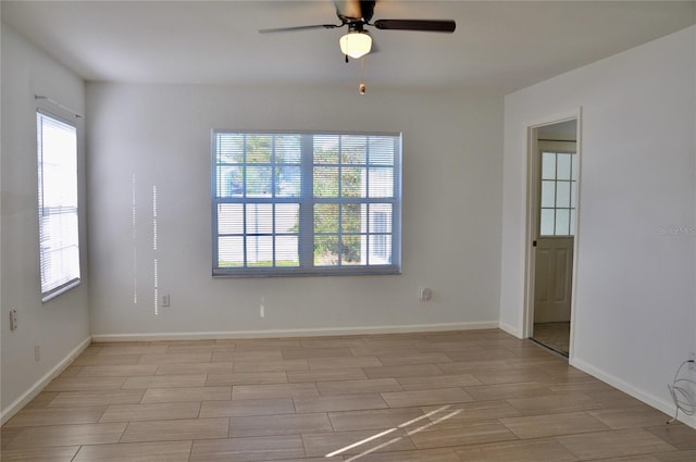 spare room with wood finish floors, ceiling fan, and baseboards