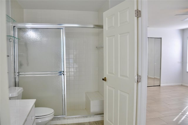 bathroom with toilet, a stall shower, vanity, and baseboards