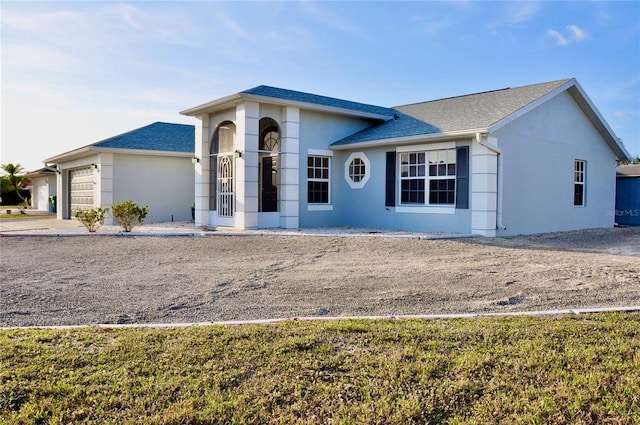 view of front of property featuring a garage, roof with shingles, and stucco siding