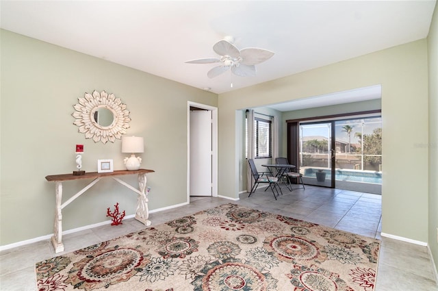 interior space with baseboards, a ceiling fan, and tile patterned floors