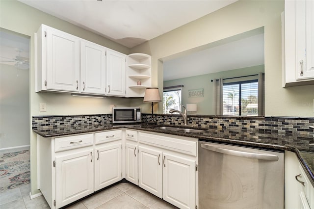 kitchen with open shelves, appliances with stainless steel finishes, white cabinetry, a sink, and dark stone counters