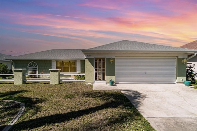 view of front of property featuring an attached garage, fence, a yard, concrete driveway, and stucco siding