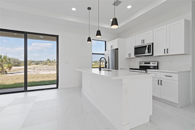 kitchen with appliances with stainless steel finishes, white cabinets, and a center island with sink