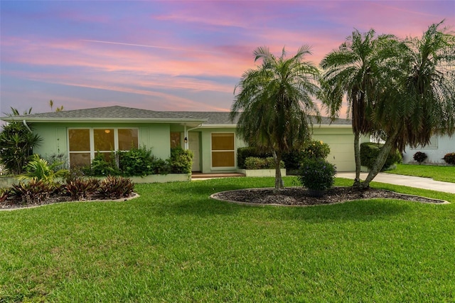 single story home with driveway, a lawn, an attached garage, and stucco siding