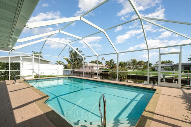 outdoor pool featuring a water view, glass enclosure, and a patio