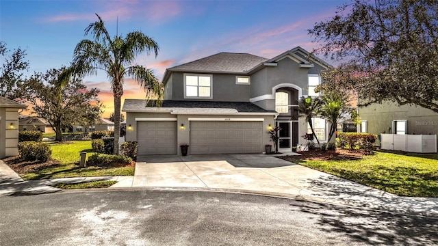 traditional-style house featuring stucco siding, a lawn, an attached garage, and driveway