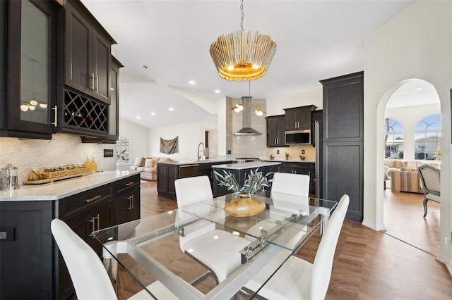 dining space with bar area, arched walkways, dark wood finished floors, and recessed lighting