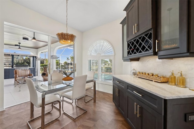 dining room featuring a ceiling fan, a dry bar, and baseboards