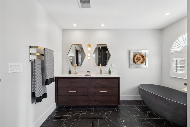 full bathroom with marble finish floor, a soaking tub, visible vents, vanity, and baseboards