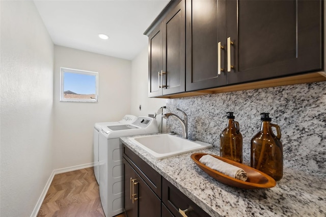 washroom with cabinet space, baseboards, washer and dryer, and a sink