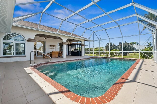 outdoor pool with glass enclosure, a ceiling fan, and a patio