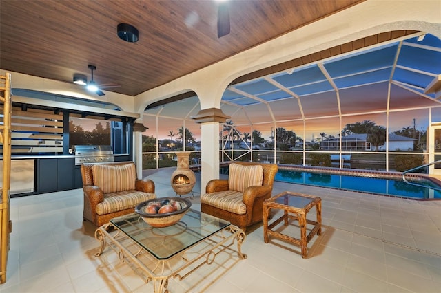 patio terrace at dusk with ceiling fan, glass enclosure, outdoor lounge area, area for grilling, and grilling area