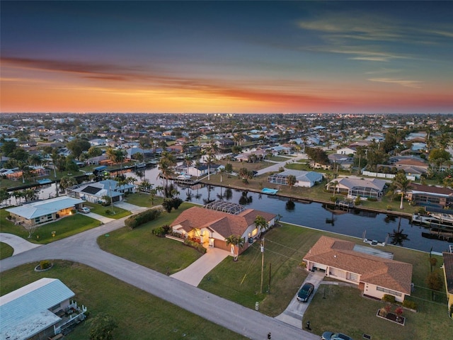 aerial view at dusk with a residential view and a water view