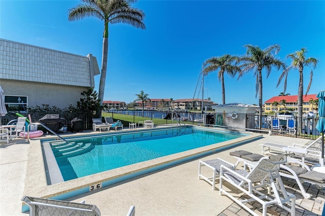 community pool featuring a patio area, fence, and grilling area