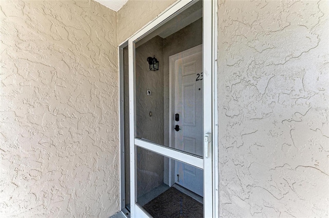 doorway to property featuring stucco siding