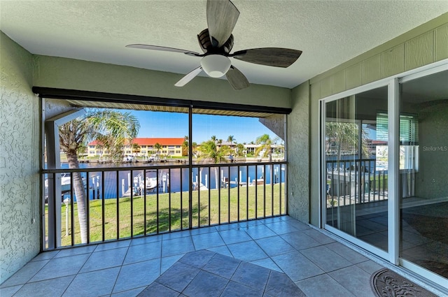 unfurnished sunroom featuring a water view and a ceiling fan