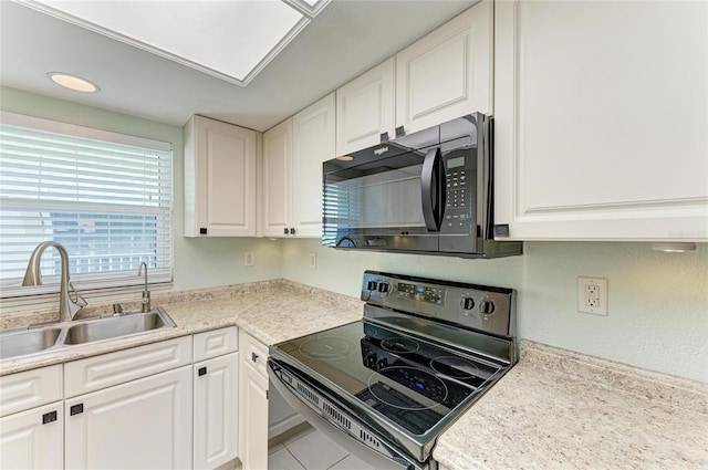 kitchen with black appliances, a sink, and white cabinets