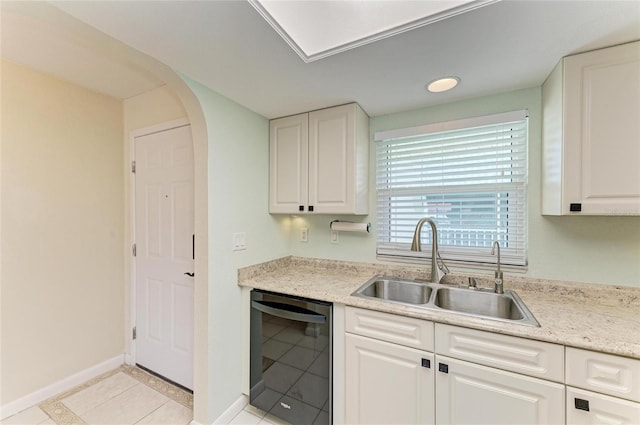 kitchen featuring black dishwasher, a sink, and white cabinets