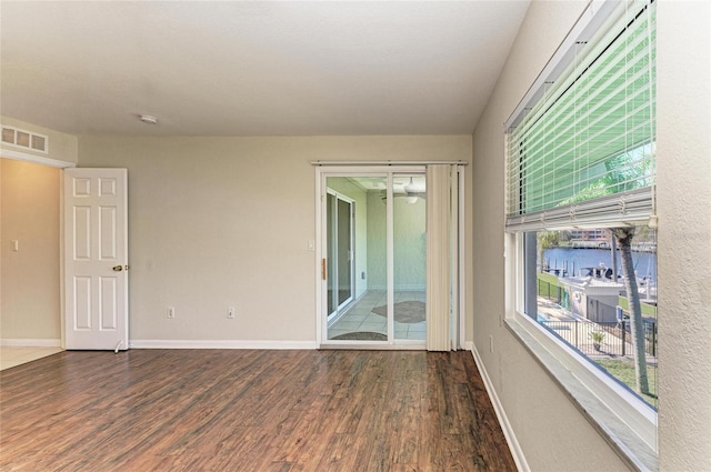 spare room featuring wood finished floors, visible vents, and baseboards