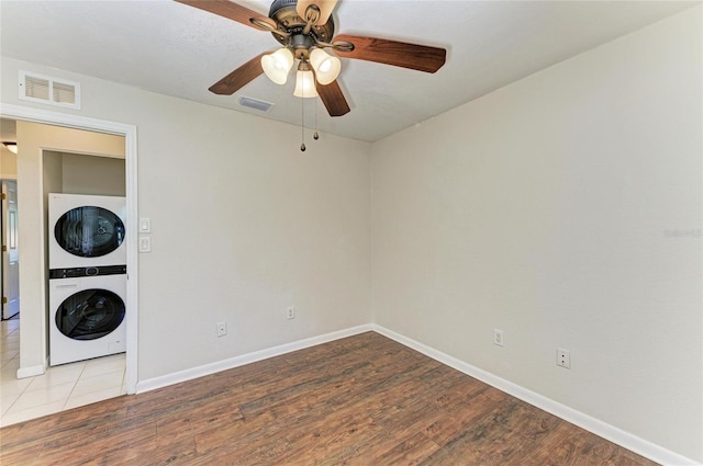 unfurnished room with visible vents, stacked washing maching and dryer, and wood finished floors