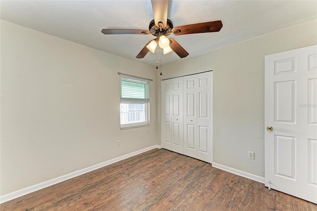 unfurnished bedroom featuring a closet, wood finished floors, a ceiling fan, and baseboards