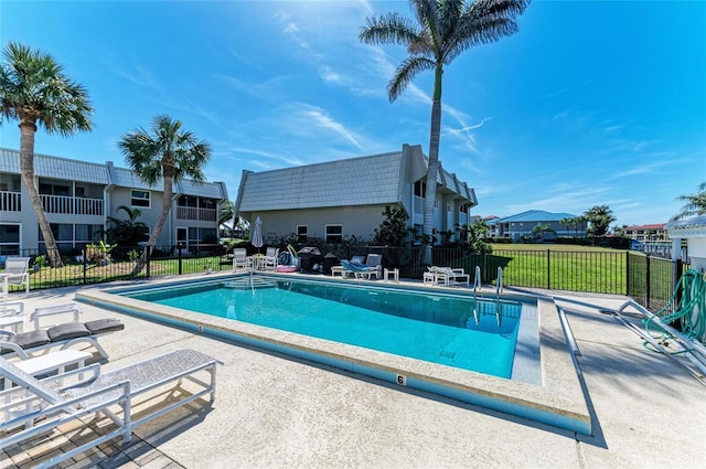 community pool featuring a patio area, fence, and a lawn