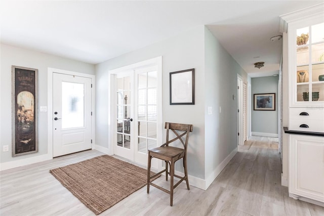 entryway with light wood-style flooring, baseboards, and french doors