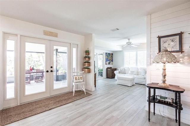 living room with a ceiling fan, light wood-type flooring, french doors, and visible vents