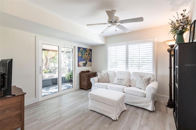 living area with light wood finished floors, ceiling fan, and baseboards