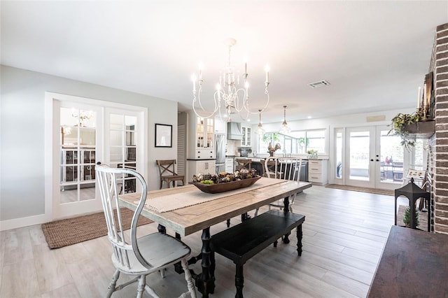 dining room with light wood-style floors, visible vents, a notable chandelier, and french doors