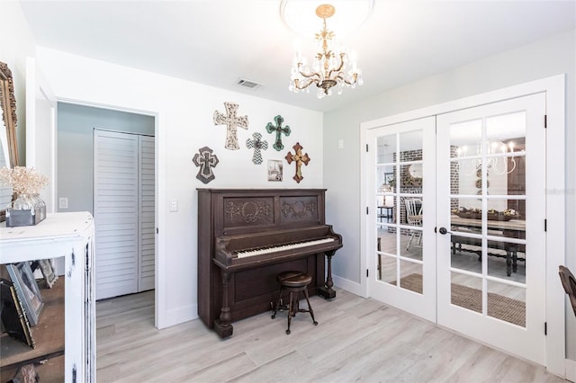 living area featuring baseboards, visible vents, an inviting chandelier, french doors, and light wood-style floors