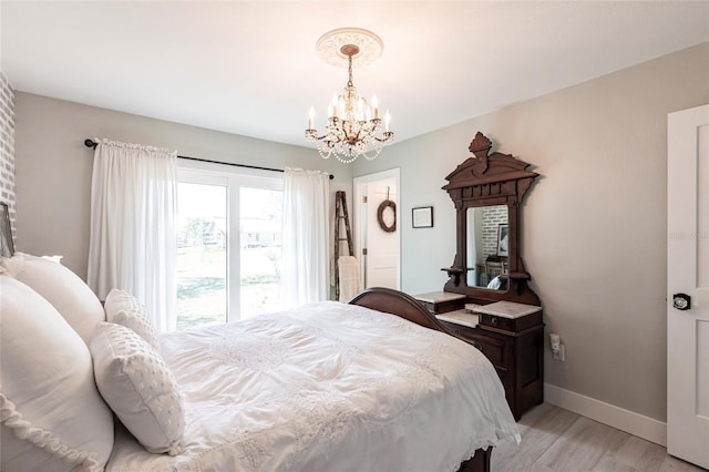 bedroom with light wood-style floors, baseboards, and an inviting chandelier