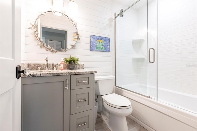 full bathroom with toilet, combined bath / shower with glass door, wood finished floors, and vanity